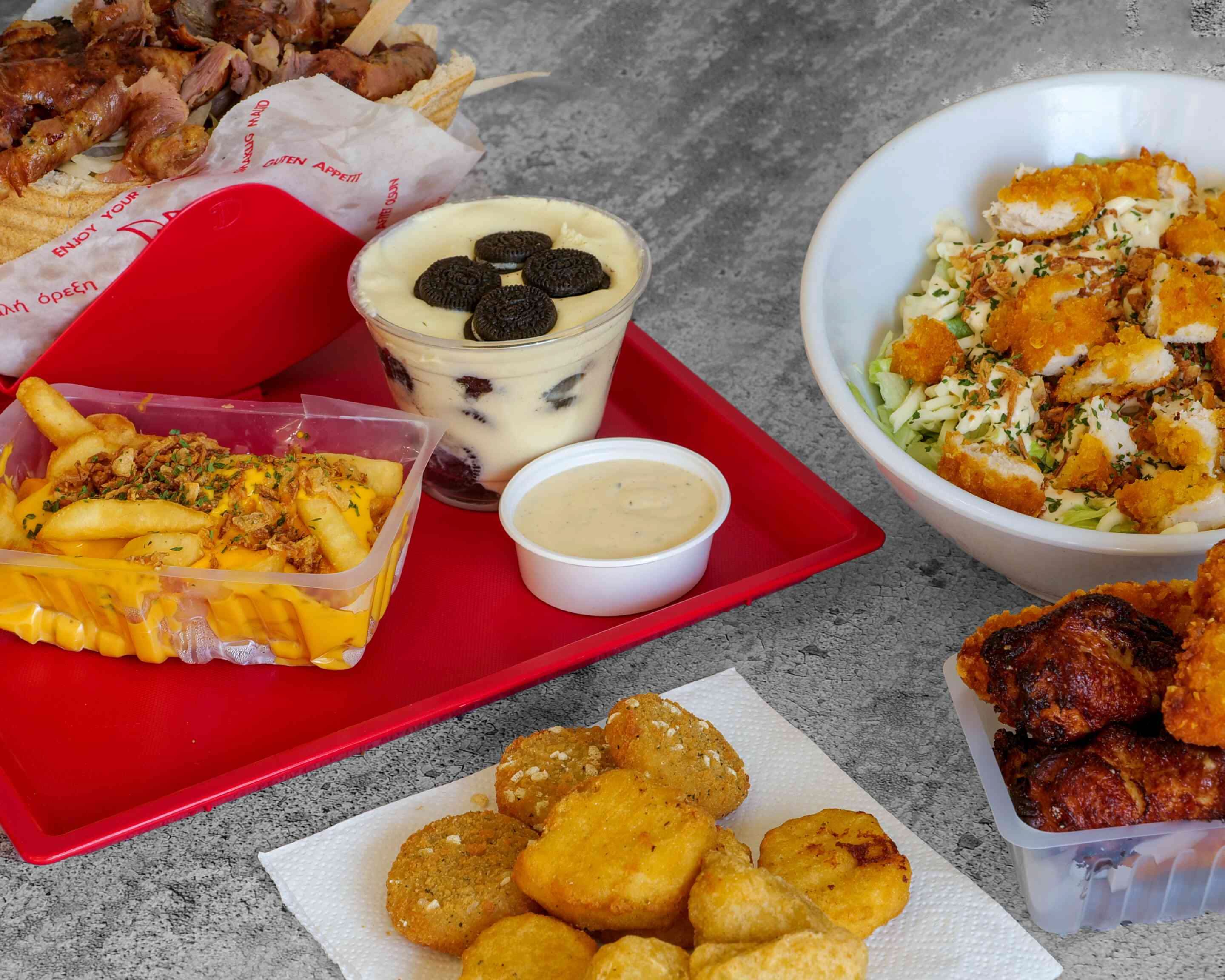 Frites au cheddar, nuggets, salade de poulet croustillant et dessert sur un plateau rouge